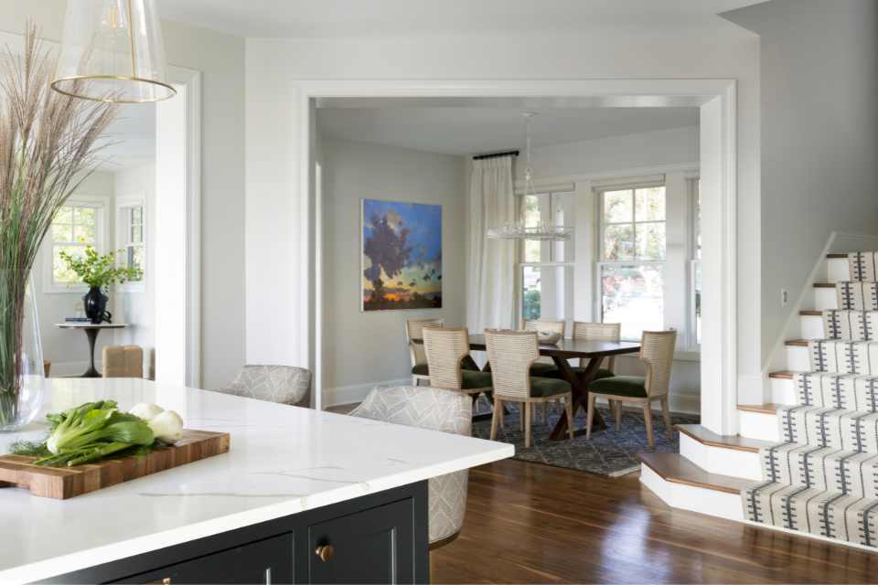 open concept kitchen into dining room with green velvet and rattan chairs